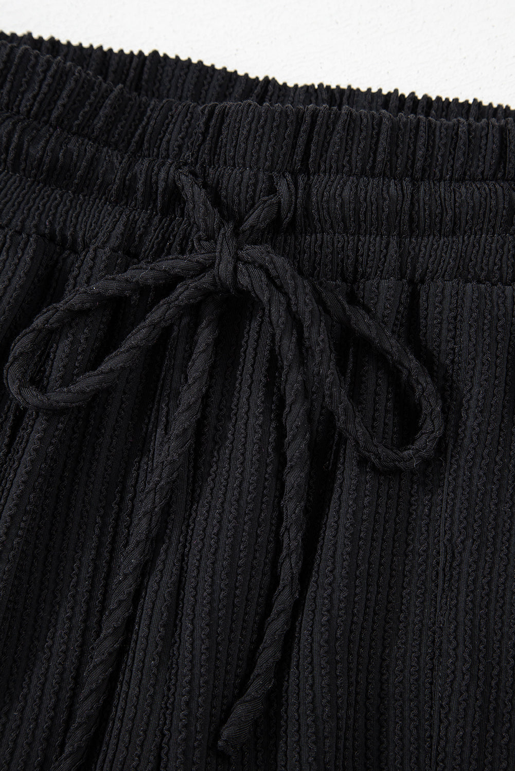 Close-up of the drawstring detail on black ribbed shorts for a cozy, stylish winter look. Perfect for online shopping.