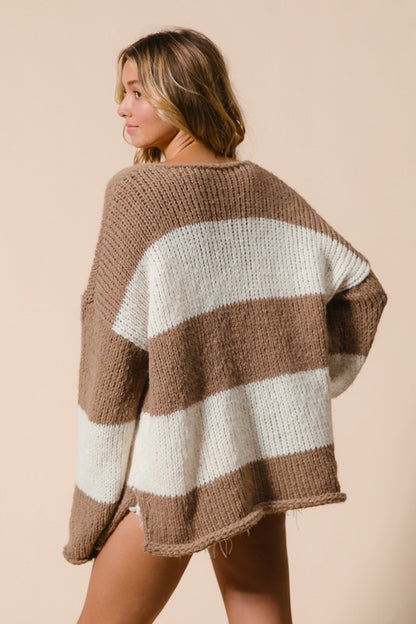 Woman wearing a cozy brown and white striped sweater, showcasing a relaxed fit and dropped shoulder design.