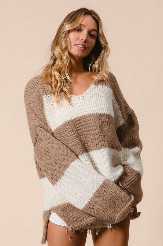 Stylish woman in a brown and white striped V-neck sweater with dropped shoulders, showcasing a trendy and relaxed fit.