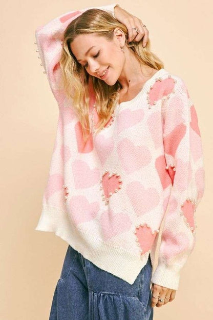 Model wearing Davi & Dani heart pearl side slit V-neck sweater featuring pink heart patterns and stylish side slits.