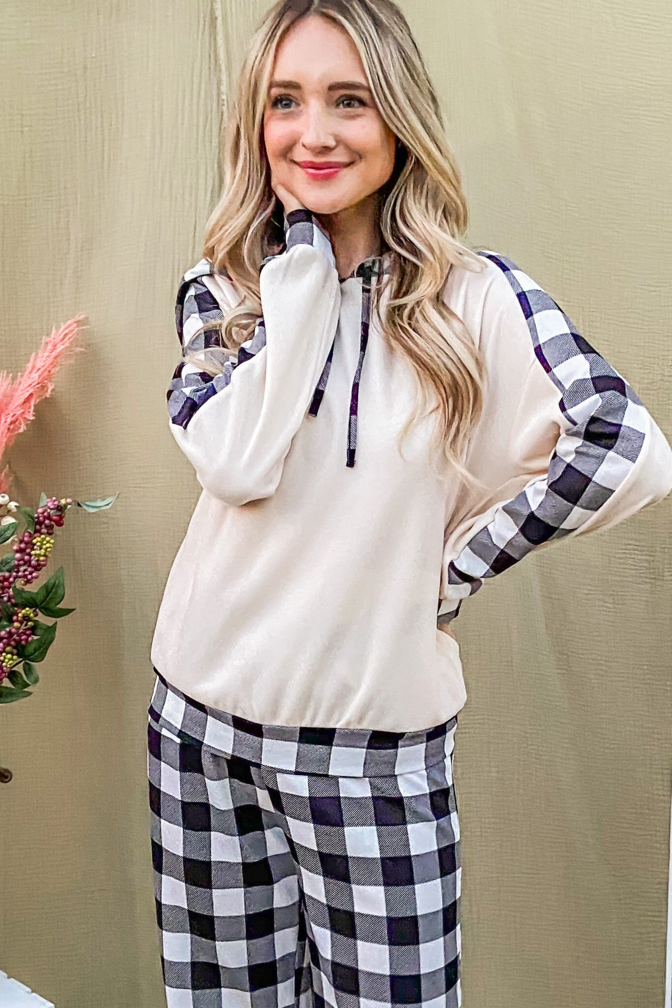 Cozy woman in beige drawstring hooded top and plaid pants, perfect for lounging and stylish new arrivals.