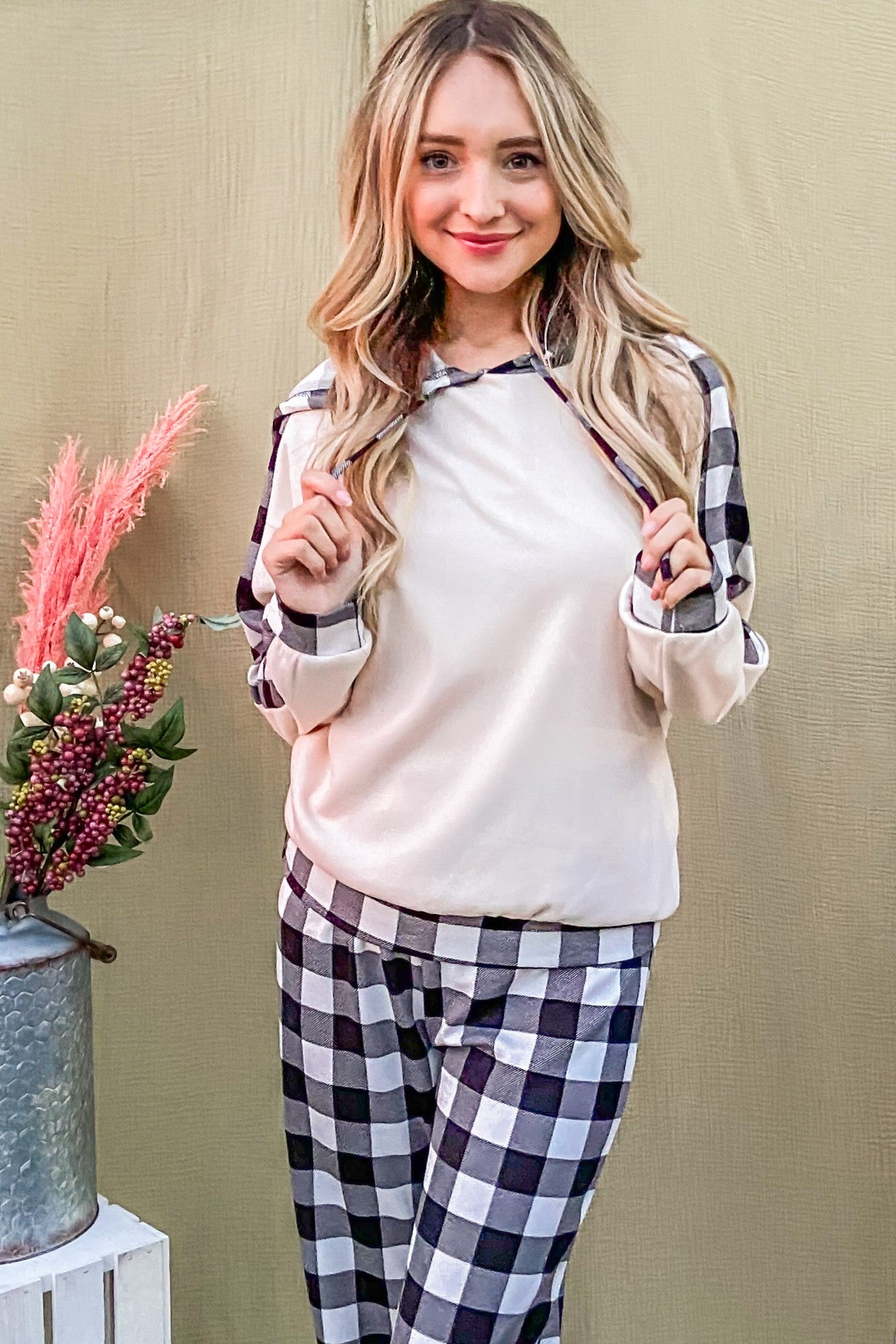 Cozy woman in drawstring hooded top and plaid pants lounge set, perfect for relaxing in style. New arrival for comfy wear.