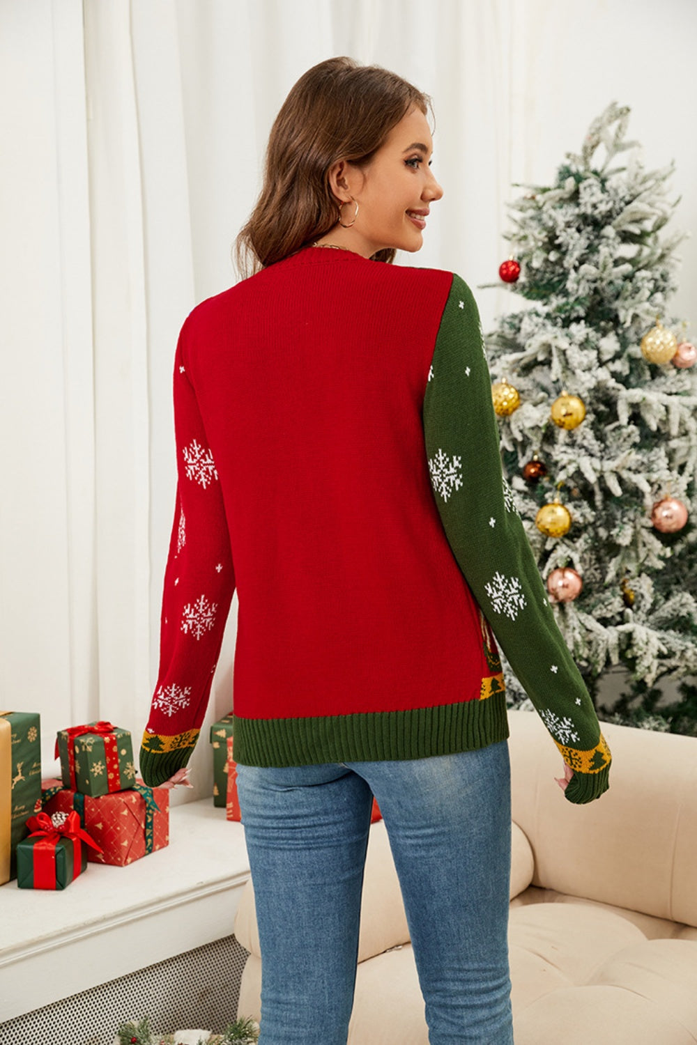 Woman in a festive red and green Nutcracker cardigan, perfect for Christmas sweaters, standing by a decorated tree.