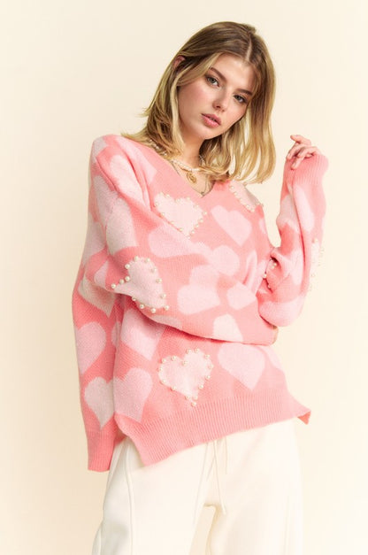 Stylish V-neck sweater with heart pearl embellishments, featuring side slits and modern pink design. Perfect for layering!