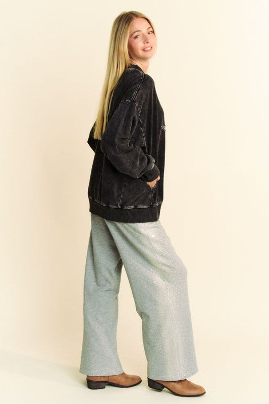 Model in a trendy Davi & Dani acid-washed sweatshirt, styled with glittery wide-leg pants and a chic ponytail.