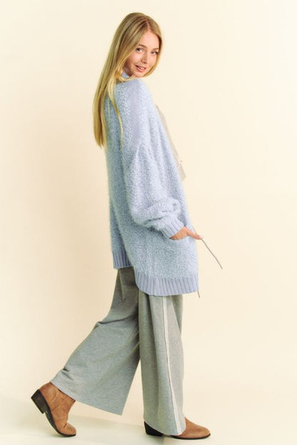 Model wearing a cozy light blue ribbed cardigan paired with gray wide-leg pants, perfect for winter layering.