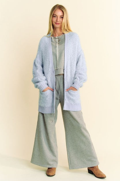 Model wearing a cozy light blue cardigan with pockets and wide-leg gray pants, perfect for winter season layering.